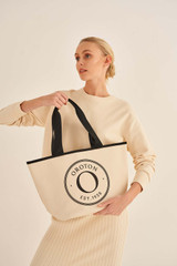 Profile view of model wearing the Oroton Kaia Mini Shopper Tote in Natural/Black and Coated Canvas for Women