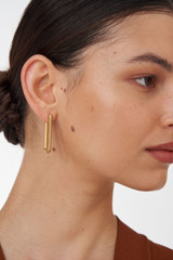 Profile view of model wearing the Oroton Lacey Large Hoops in Worn Gold and Brass Base With 18CT Gold Plating for Women