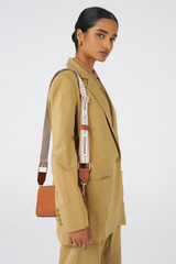 Profile view of model wearing the Oroton Heather Long Webbing Strap in Cognac/Natural and Polyester webbing strap and pebble leather trim for Women