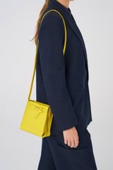 Profile view of model wearing the Oroton Margot Tiny Bucket Bag in Sunshine and Pebble leather for Women