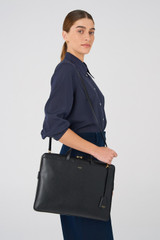Profile view of model wearing the Oroton Muse Apple 15" Slim Laptop Bag in Black and Vegan leather for Women