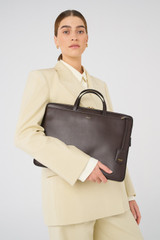 Profile view of model wearing the Oroton Muse Apple 15" Slim Laptop Bag in Dark Chocolate and Vegan leather for Women