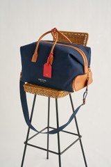 Profile view of model wearing the Oroton Voyager Weekender in Yacht Blue/Brandy and Canvas and leather trims for Women