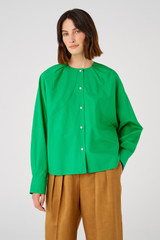 Profile view of model wearing the Oroton Cape Blouse in Jewel Green and 100% cotton for Women