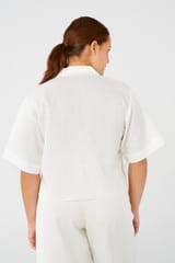 Profile view of model wearing the Oroton Lily Embroidered Shirt in White and 100% linen for 