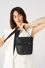 Profile view of model wearing the Oroton Post Bucket Bag in Black and Pebble leather with smooth leather trims for Women