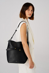 Profile view of model wearing the Oroton Post Hobo in Black and Pebble leather with smooth leather trims for Women