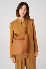 Profile view of model wearing the Oroton Post Hobo in Amber/Cognac and Pebble leather with smooth leather trims for Women
