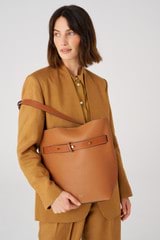 Profile view of model wearing the Oroton Post Hobo in Amber/Cognac and Pebble leather with smooth leather trims for Women