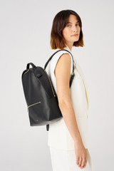 Profile view of model wearing the Oroton Margot Zip Backpack in Black and Pebble leather for Women
