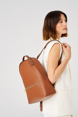 Profile view of model wearing the Oroton Margot Zip Backpack in Whiskey and Pebble leather for Women