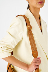 Profile view of model wearing the Oroton Logo Webbing Bag Strap in Amber and Smooth leather for Women