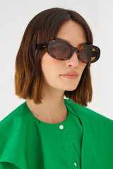 Profile view of model wearing the Oroton Daphne Sunglasses in Signature Tort and Acetate for Women
