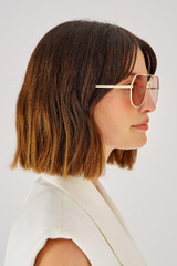 Profile view of model wearing the Oroton Valo Sunglasses in Eggshell and Metal for Women