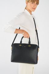 Profile view of model wearing the Oroton Anika 14" Laptop Bag in Black and Pebble Leather for Women