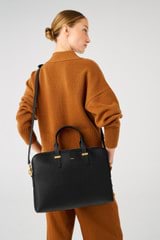 Profile view of model wearing the Oroton Anika 16" Laptop Bag in Black and Pebble Leather for Women