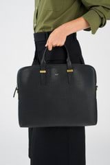 Profile view of model wearing the Oroton Anika 16" Laptop Bag in Black and Pebble Leather for Women