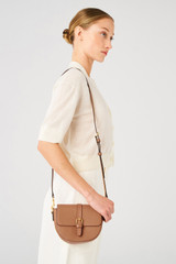 Profile view of model wearing the Oroton Dylan Small Saddle Bag in Tan and Pebble leather, smooth leather trims for Women