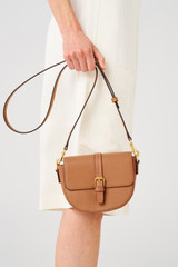 Profile view of model wearing the Oroton Dylan Small Saddle Bag in Tan and Pebble leather, smooth leather trims for Women
