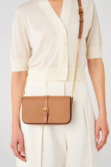 Profile view of model wearing the Oroton Dylan Clutch Crossbody in Tan and Pebble leather, smooth leather trims for Women