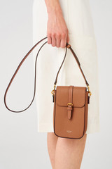 Profile view of model wearing the Oroton Dylan Buckle Phone Crossbody in Tan and Pebble leather, smooth leather trims for Women