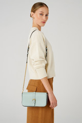 Profile view of model wearing the Oroton Dylan Clutch Crossbody in Duck Egg and Pebble leather, smooth leather trims for Women