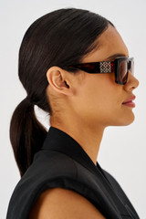 Profile view of model wearing the Oroton Alice Sunglasses in Signature Tort and Acetate for Women