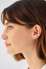 Profile view of model wearing the Oroton Fife Huggies in 18K Gold and Sustainably sourced 925 Sterling Silver for Women