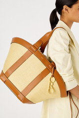 Profile view of model wearing the Oroton Harper Large Tote in Natural/Brandy and Woven straw with smooth leather trims for Women