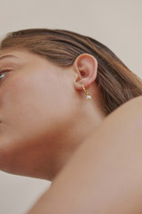 Profile view of model wearing the Oroton Melody Single Pearl Huggies in 18K Gold and Recycled 925 Sterling Silver for Women