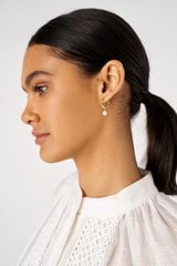 Profile view of model wearing the Oroton Melody Single Pearl Huggies in 18K Gold and Sustainably sourced 925 Sterling Silver for Women