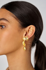 Profile view of model wearing the Oroton Conch Drop Earrings in Worn Gold and Brass for Women