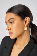 Profile view of model wearing the Oroton Frankie Drop Earrings in Worn Gold/Clear and Brass for Women