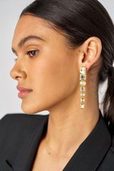 Profile view of model wearing the Oroton Frankie Long Drop Earrings in Worn Gold/Clear and Brass for Women