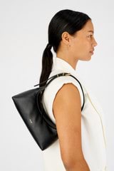 Profile view of model wearing the Oroton Cinder Mini Baguette in Black and Smooth leather for Women