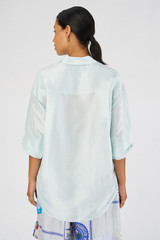 Profile view of model wearing the Oroton Silk Long Sleeve Shirt in Pale Blue and 100% silk for Women
