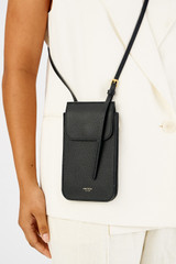 Profile view of model wearing the Oroton Margot Phone Crossbody in Black and Pebble leather for Women