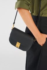 Profile view of model wearing the Oroton Yvonne Small Saddle Bag in Black and Pebble Leather for Women