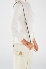 Profile view of model wearing the Oroton Yvonne Small Saddle Bag in Cream and Pebble Leather for Women
