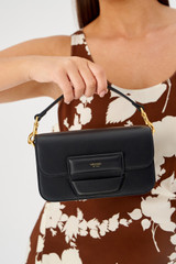 Profile view of model wearing the Oroton Dahlia Mini Day Bag in Black and Smooth leather for Women