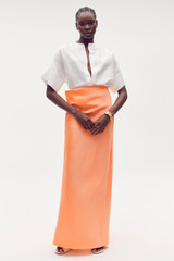 Profile view of model wearing the Oroton Drape Back Skirt in Bright Melon and 85% polyester, 15% silk for Women