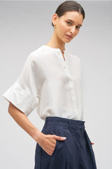 Profile view of model wearing the Oroton Short Sleeve Silk Dupion Overshirt in White and 100% silk for Women