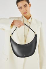 Profile view of model wearing the Oroton Penny Small Shoulder Bag in Black and Smooth leather for Women