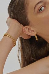 Profile view of model wearing the Oroton Fife Bangle in 18K Gold and Sustainably sourced 925 Sterling Silver for Women