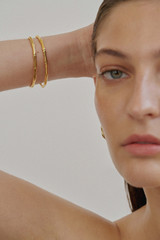 Profile view of model wearing the Oroton Fife Bangle in 18K Gold and Sustainably sourced 925 Sterling Silver for Women