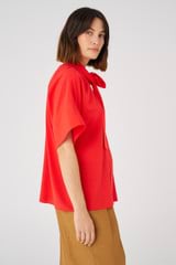 Profile view of model wearing the Oroton Silk Blouse in Poppy and 92% silk, 8% spandex for Women