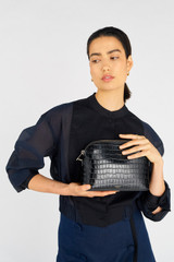 Profile view of model wearing the Oroton Inez Texture Slim Crossbody in Black Croc and Embossed Leather for Women