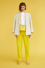 Profile view of model wearing the Oroton Pleat Pant in Vivid Yellow and 58% Viscose, 42% Linen for Women