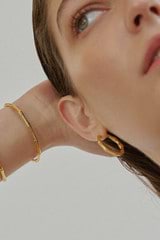 Profile view of model wearing the Oroton Fife Large Hoops in 18K Gold and Sustainably sourced 925 Sterling Silver for Women