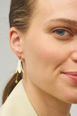 Profile view of model wearing the Oroton Lilium Drop Earrings in Gold/Clotted Cream and Brass for Women